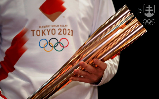 Olympijská pochodeň pre Tokio 2020 v rukách bežca v tričku s dizajnom štafety.