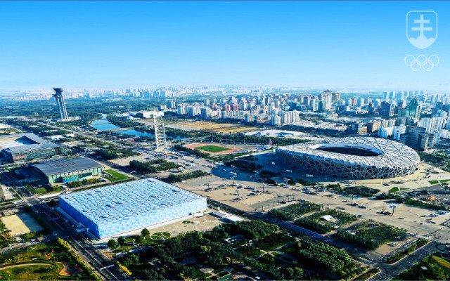 Pohľad na časť Pekingu, ktorej dominujú dve ikonické športoviská, postavené k OH 2008. V popredí tzv. Vodná kocka, ktorá sa počas ZOH 2022 zmení na Ľadovú kocku a uskutoční sa tam turnaj v curlingu. Na monumentálnom Národnom štadióne sa uskutoční otvárací aj záverečný ceremoniál ZOH 2022.