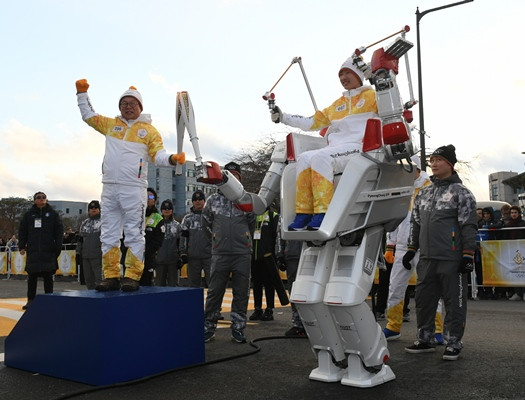 Professor O Jun-ho odovzdáva plameň robotovi FX-2. FOTO: POCOG